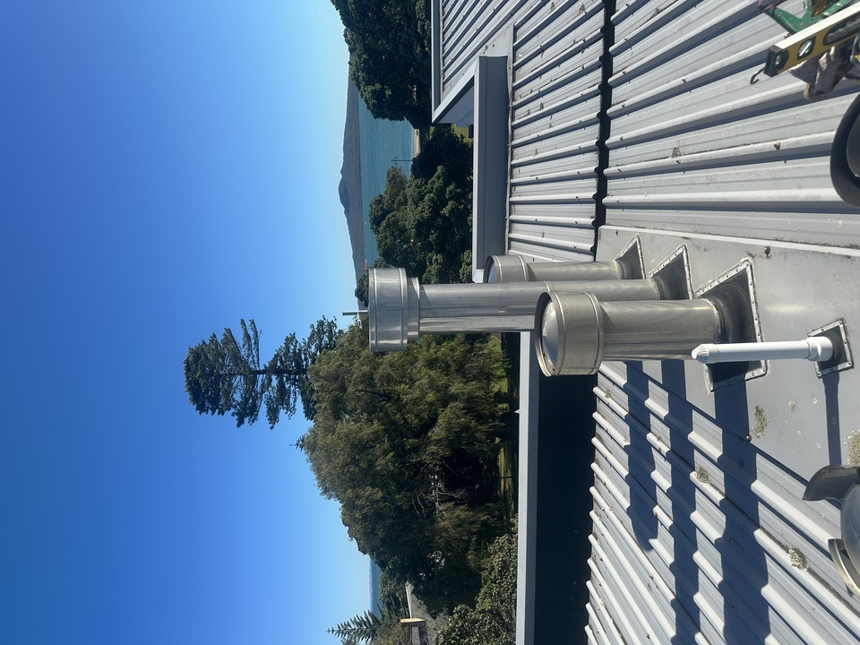 Gas flue on top of house in Mission Bay with Rangitoto island in background